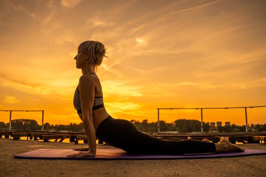 Woman practicing yoga in sunset. Bhujangasana/Cobra Pose