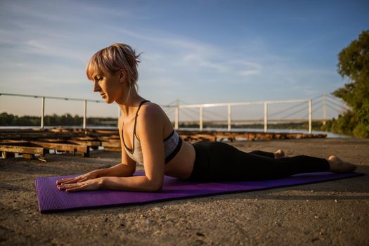 Woman practicing yoga on sunny day. Bhujangasana, Cobra pose.