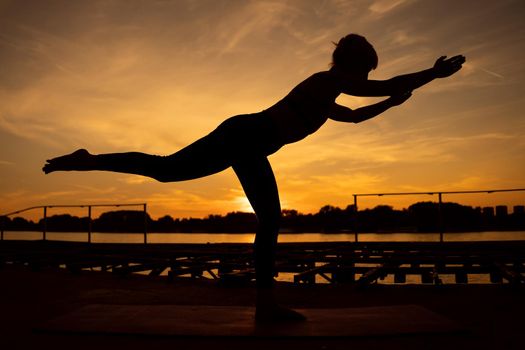 Woman practicing yoga in sunset. Virabhadrasana / Warrior pose