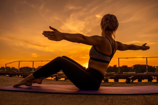 Woman exercising pilates in sunset.