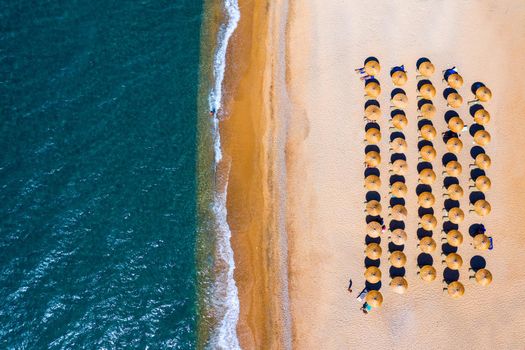 View from above, stunning aerial view of an amazing beach with beach umbrellas and turquoise clear water. Top view on sun loungers under umbrellas on the sandy beach. Concept of summer vacation. 