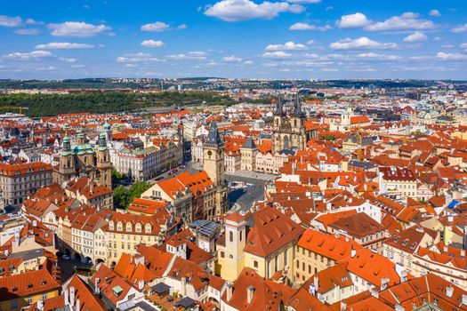 Prague beautiful panoramic sunny aerial drone view above Prague Old Town Square with Church of Our Lady before Tyn and Prague Astronomical Clock Tower. Drone flight over red roofs of Prague, Czechia.