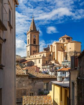 Picturesque street with the Duomo in the background in Novara di Sicilia, Sicily, Italy. Amazing cityscape of Novara di Sicilia town. Mountain village Novara di Sicilia, Sicily, Italy.