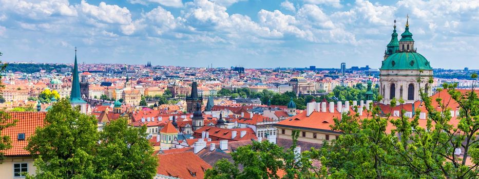 Prague red roofs and dozen spires of historical Old Town of Prague. Cityscape of Prague on a sunny day. Red rooftops, spires and the Charles Bridge and Vltava River in the background. Prague, Czechia.