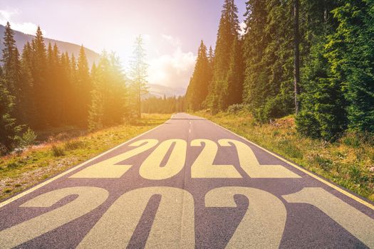 Empty asphalt road and New year 2022 concept. Driving on an empty road in the mountains to upcoming 2022 and leaving behind old 2021. Concept for success and passing time.