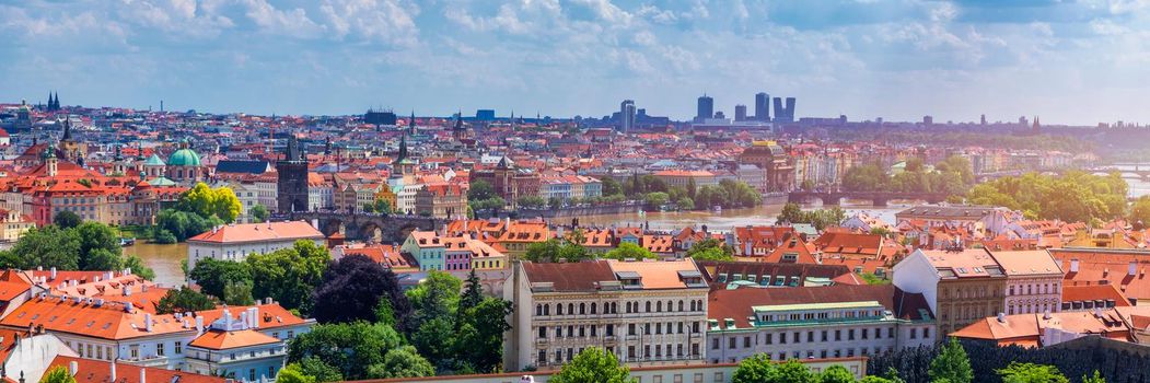 Prague red roofs and dozen spires of historical Old Town of Prague. Cityscape of Prague on a sunny day. Red rooftops, spires and the Charles Bridge and Vltava River in the background. Prague, Czechia.