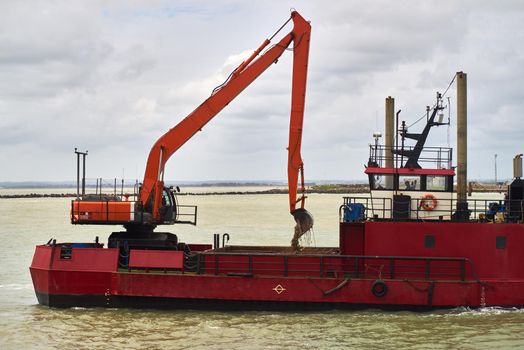 Mud is loaded into the hopper of a dredging barge