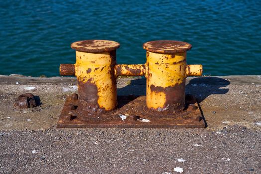 The rusty mooring bitt is used to secure boats and ships to a port or harbour.