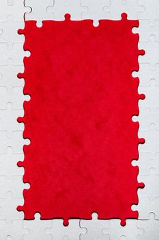 Framing in the form of a rectangle, made of a white jigsaw puzzle. Frame text and jigsaw puzzles. Frame made of jigsaw puzzle pieces on red background.