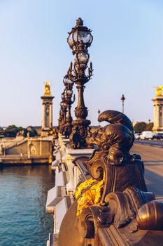 Pont Alexandre III bridge over river Seine in the sunny summer morning. Bridge decorated with ornate Art Nouveau lamps and sculptures. The Alexander III Bridge across Seine river in Paris, France.