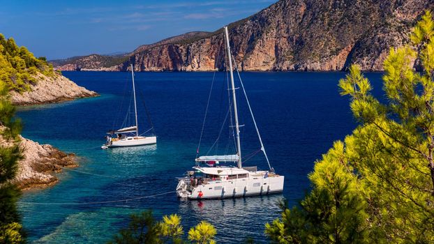 Aerial view of anchored sailing yacht in emerald sea. Aerial view of a boat. Outdoor water sports, yachting. Aerial view of anchoring yacht in open water. Ocean and sea travel and transportation