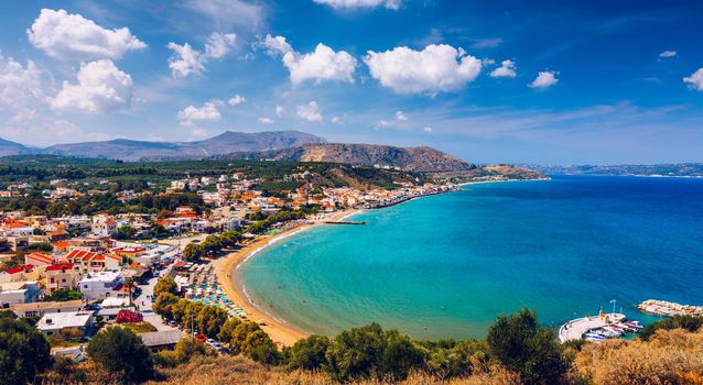 Greek holidays, beautiful Kalyves village with turquoise sea in Crete island, Greece. View of Kalyves beach, Crete. Tourists relaxing on the beach and views to the mountains, Kalyves, Crete, Greece