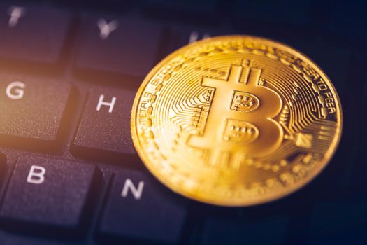 Bitcoin on compuer keyboard in background, symbol of electronic virtual money and mining cryptocurrency concept. Coin crypto currency bitcoin lies on the keyboard. Bitcoin on keyboard.