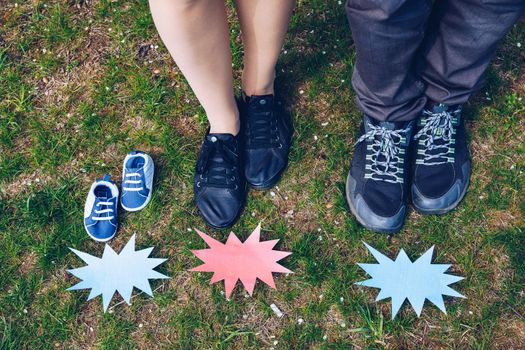 Young couple waiting for baby. Expecting parents with little baby boy shoes. Concept of Parents-To-Be. Shoes and sneakers of parents and expected baby. Mom, dad and the future baby Shoes.