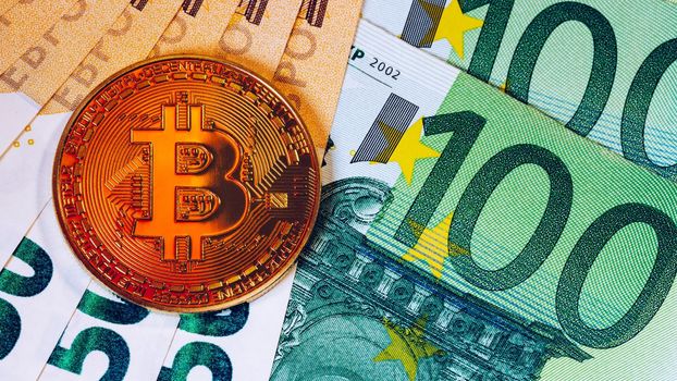 Golden bitcoin over Euro money. Bitcoin cryptocurrency. Crypto currency concept. Bitcoin with euro bills. Bitcoins stacked on euro banknotes.