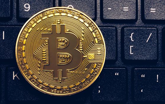 Bitcoin on compuer keyboard in background, symbol of electronic virtual money and mining cryptocurrency concept. Coin crypto currency bitcoin lies on the keyboard. Bitcoin on keyboard.