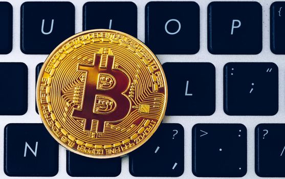 Bitcoin on compuer keyboard in background, symbol of electronic virtual money and mining cryptocurrency concept. Coin crypto currency bitcoin lies on the keyboard. Bitcoin on keyboard.