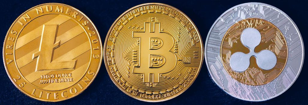 Bitcoin, litecoin and ripple coins currency finance money on graph chart background. Bitcoin as most important cryptocurrency concept. Stack of cryptocurrencies with a golden bitcoin in the middle.