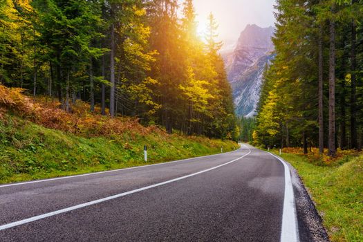 Mountain road. Landscape with rocks, sunny sky with clouds and beautiful asphalt road in the evening in summer. Vintage toning. Travel background. Highway in mountains.  