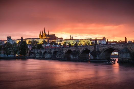 Skyline of Charles bridge and Prague castle on Vltava river during afternoon. Storm clouds with red color. Old Town, Prague, Europe.