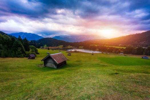 Panoramic morning scene of Wagenbruchsee (Geroldsee) lake with Zugspitze mountain range on background. Amazing autumn view of Bavarian Alps, Germany, Europe. Wooden hut on meadow by Geroldsee lake. 