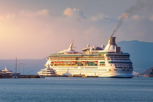 Cruise ship at harbor. Beautiful large white ship at sunset. Colorful landscape with cruiser in marina bay, sea, colorful sky. Luxury cruise ship leaving port at sunset.