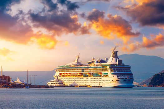 Cruise ship at harbor. Beautiful large white ship at sunset. Colorful landscape with cruiser in marina bay, sea, colorful sky. Luxury cruise ship leaving port at sunset.