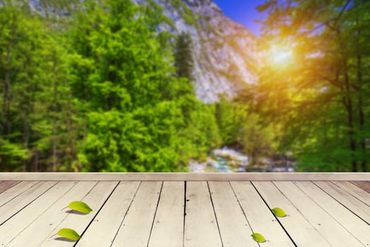 Empty wooden table for product placement or montage with focus to table top in the foreground. Mock up for display of product. Beautiful background with forest, waterfall, incredible landscape.
