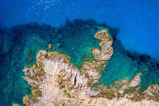 Aerial photo over granite rocky coastline Mediterranean crystal clear blue sea water. Aerial photo of ocean waves hitting rocky coastline of beautiful paradise dream tropical beach. Sardinia, Italy.