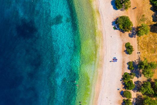 Concept of summer vacation. View from above, stunning aerial view of an amazing beach with beach umbrellas and turquoise clear water. Top view on a sun lounger under an umbrella on the sandy beach
