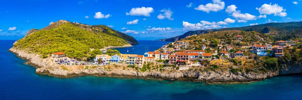Turquoise colored bay in Mediterranean sea with beautiful colorful houses in Assos village in Kefalonia, Greece. Town of Assos with colorful houses on the mediterranean sea, Greece. 