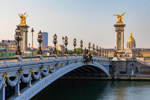Pont Alexandre III bridge over river Seine in the sunny summer morning. Bridge decorated with ornate Art Nouveau lamps and sculptures. The Alexander III Bridge across Seine river in Paris, France.