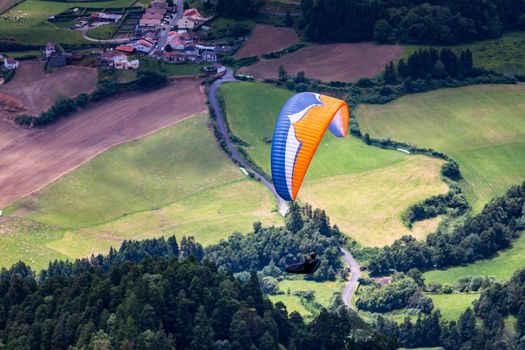 Paragliding in paradise landscape with volcano crater and lagoon in Azores. Paraglider above Lagoa das Furnas, Sao Miguel, Azores, Portugal, Europe