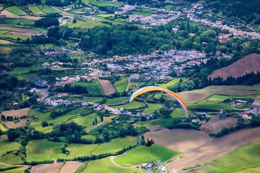 Paragliding in paradise landscape with volcano crater and lagoon in Azores. Paraglider above Lagoa das Furnas, Sao Miguel, Azores, Portugal, Europe