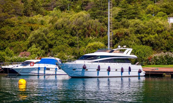 Yacht anchoring in crystal clear turquoise water in front of the tropical island, alternative lifestyle, living on a boat. Aerial view of yacht at anchor on turquoise water, showing luxury, wealth.