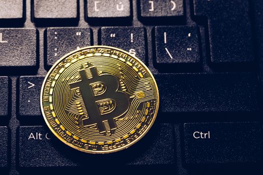 Bitcoin on compuer keyboard in background, symbol of electronic virtual money and mining cryptocurrency concept. Coin crypto currency bitcoin lies on the keyboard. Bitcoin on keyboard.