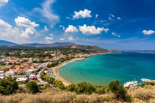 Greek holidays, beautiful Kalyves village with turquoise sea in Crete island, Greece. View of Kalyves beach, Crete. Tourists relaxing on the beach and views to the mountains, Kalyves, Crete, Greece