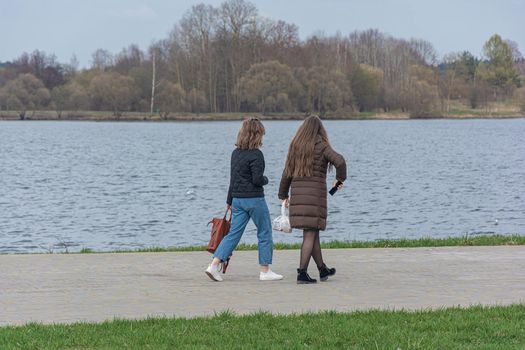 Two girls are walking along the embankment along the river. Stock photography.