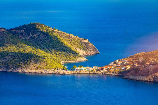 Turquoise colored bay in Mediterranean sea with beautiful colorful houses in Assos village in Kefalonia, Greece. Town of Assos with colorful houses on the mediterranean sea, Greece. 