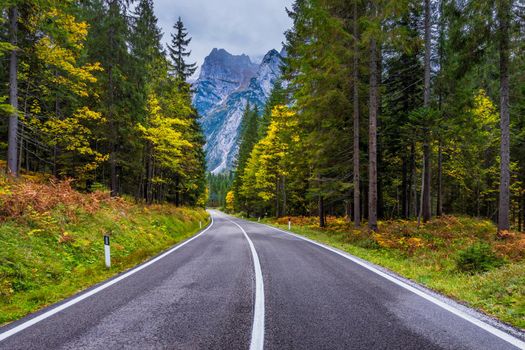 Mountain road. Landscape with rocks, sunny sky with clouds and beautiful asphalt road in the evening in summer. Vintage toning. Travel background. Highway in mountains.  