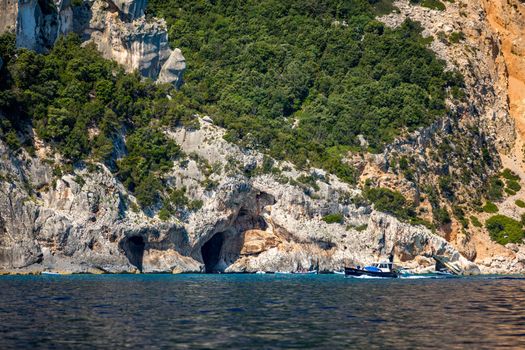 Blue sea and the characteristic caves of Cala Luna, a beach in the Golfo di Orosei, Sardinia, Italy. Big sea caves in the mediterranean coast. Sardinia, Italy.