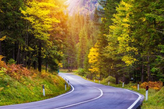 Mountain road. Landscape with rocks, sunny sky with clouds and beautiful asphalt road in the evening in summer. Vintage toning. Travel background. Highway in mountains.  