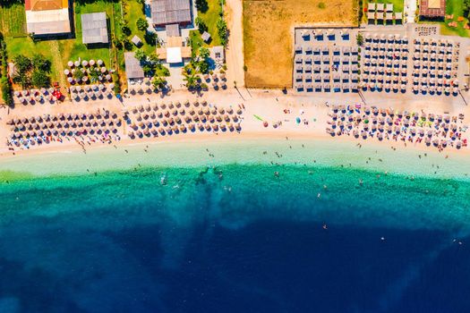 Concept of summer vacation. View from above, stunning aerial view of an amazing beach with beach umbrellas and turquoise clear water. Top view on a sun lounger under an umbrella on the sandy beach