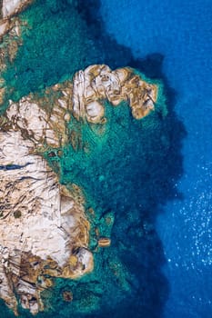 Aerial photo over granite rocky coastline Mediterranean crystal clear blue sea water. Aerial photo of ocean waves hitting rocky coastline of beautiful paradise dream tropical beach. Sardinia, Italy.