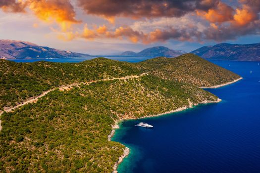 Yacht anchoring in crystal clear turquoise water in front of the tropical island, alternative lifestyle, living on a boat. Aerial view of yacht at anchor on turquoise water, showing luxury, wealth.