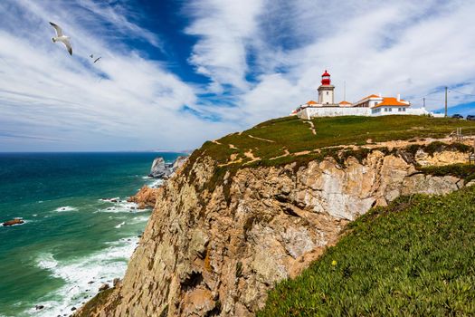 The lighthouse in Cabo da Roca. Cliffs and rocks on the Atlantic ocean coast in Sintra in a beautiful summer day, Portugal. Cabo da Roca, Portugal. Lighthouse and cliffs over Atlantic Ocean.
