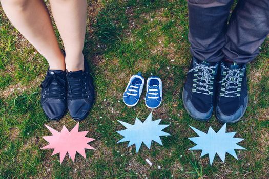 Young couple waiting for baby. Expecting parents with little baby boy shoes. Concept of Parents-To-Be. Shoes and sneakers of parents and expected baby. Mom, dad and the future baby Shoes.
