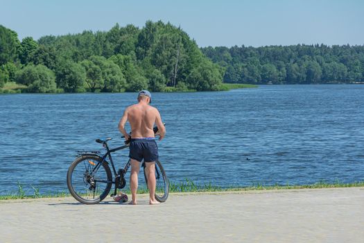 man with a bicycle stands on the embankment near the river, Blurred background. Stock photography.
