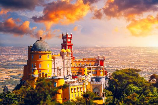 Famous historic Pena palace part of cultural site of Sintra against sunset sky in Portugal. Panoramic View Of Pena Palace, Sintra, Portugal. Pena National Palace at sunset, Sintra, Portugal. 