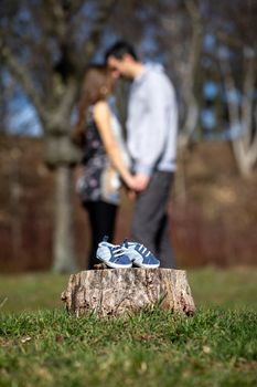Young couple waiting for baby. Expecting parents with little baby boy shoes. Concept of Parents-To-Be. Shoes and sneakers of parents and expected baby. Mom, dad and the future baby Shoes.